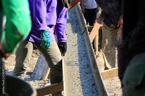 Construction workers are working on concrete, building structures.