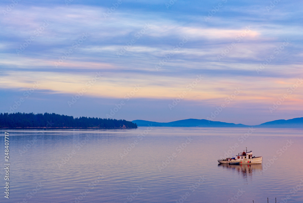 View of the sunset at the ocean with small boat in Vancouver Island, Canada