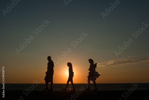 family group of people together walking along sea shore during beautiful sunset travel