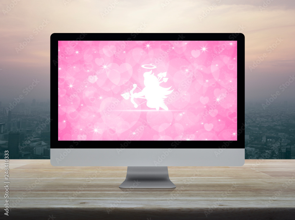 Cupid flat icon on desktop modern computer monitor with love heart screen  on wooden table over