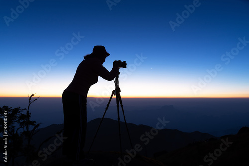 Silhouette of woman shooting with camera at sunset . Travel Concept