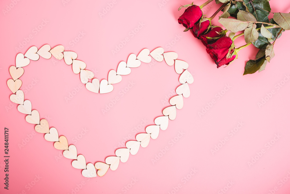 Wood hearts on pink background have a flower rose