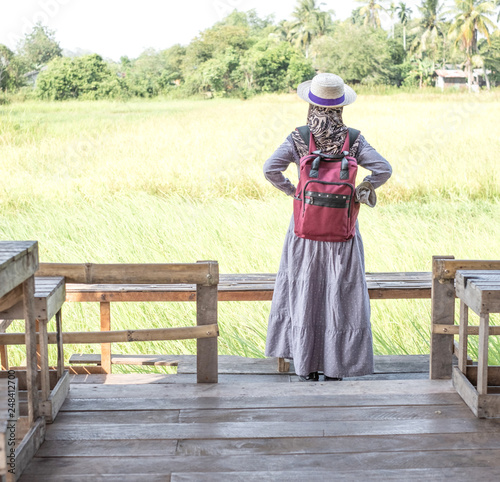 Muslim woman traveler enjoy panorama view of beautiful Asian scenery of nature field cottage. Coffee shop in rice field. Trip to Thailand.