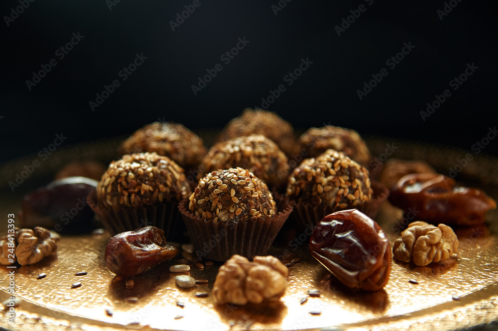 Healthy snacks, fitness lifestyle and high fiber diet concept with granola energy bars surrounded by dried fruits, hazelnuts and almonds on a black stone with dramatic light Healthy snacks, fitness lifestyle and high fiber diet concept with granola energy bars surrounded by dried fruits, hazelnuts and almonds on a black stone with dramatic light