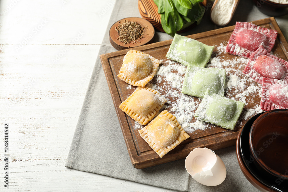 Wooden board with uncooked ravioli on table Wooden board with uncooked ravioli on table