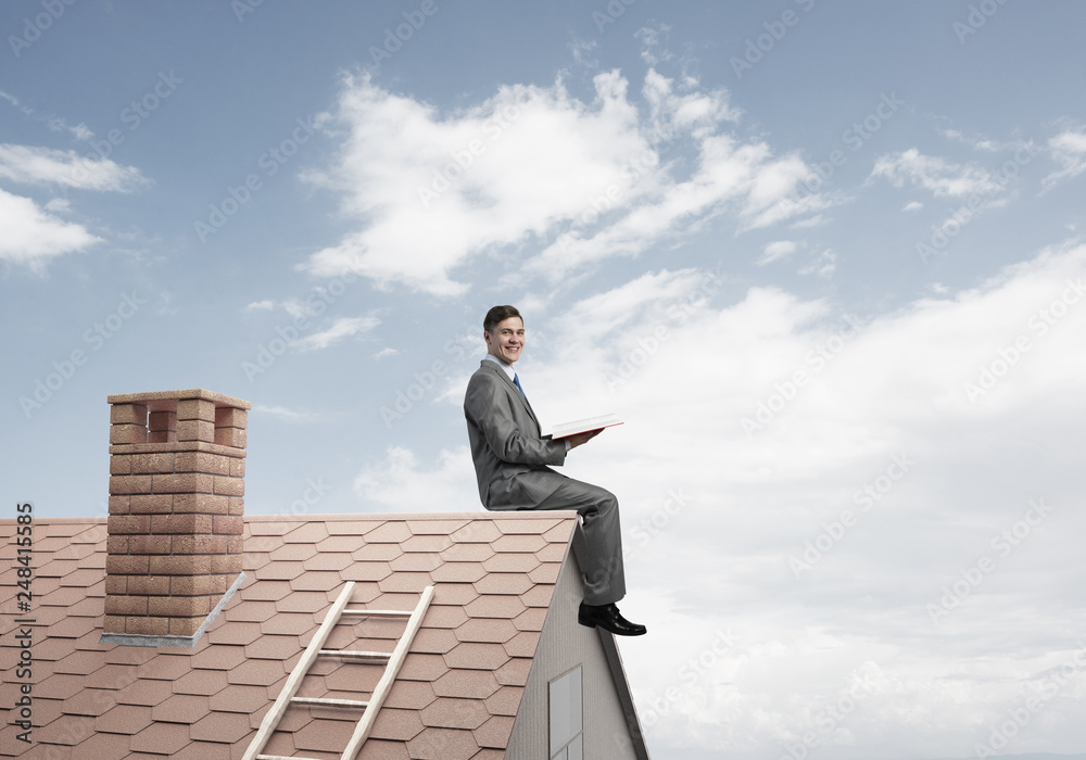 Student guy in suit on brick house roof reading book Student guy in suit on brick house roof reading book