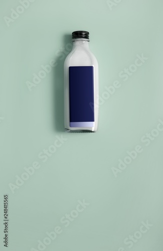 Glass bottle with white liquid (milk, cream, sauce) isolated on colour background
