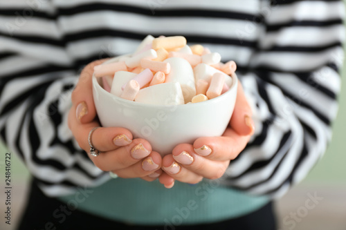 Young woman holding bowl with tasty marshmallows, closeup