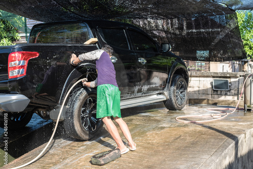 Man worker wash car. Car washing using high pressure water and sponge.