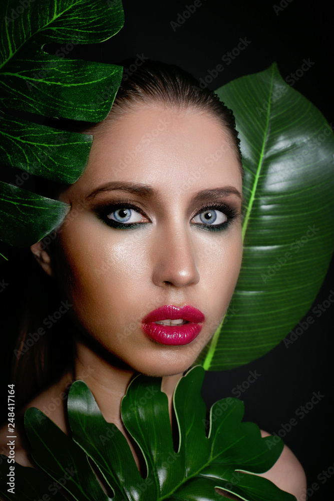 Studio beauty portrait of a beautiful girl in tropical leaves.. Studio beauty portrait of a beautiful girl in tropical leaves..