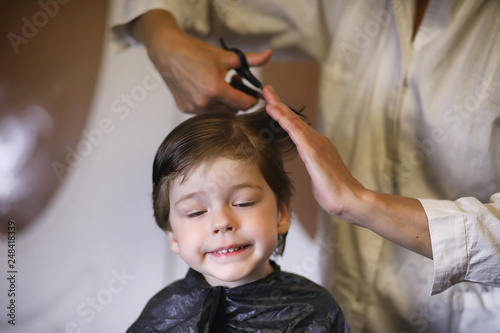 Hairdresser and boy. The boy is doing his hair. Cut hair child in the hairdresser.