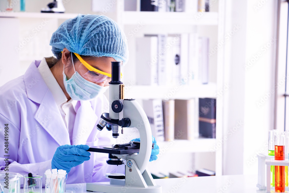 Young Asia woman scientist working in laboratory.She is looking microscope.She is trying and research with red and blue test tube. Experiment , chemical Photo concept develop and medicine. Young Asia woman scientist working in laboratory.She is looking microscope.She is trying and research with red and blue test tube. Experiment , chemical Photo concept develop and medicine.