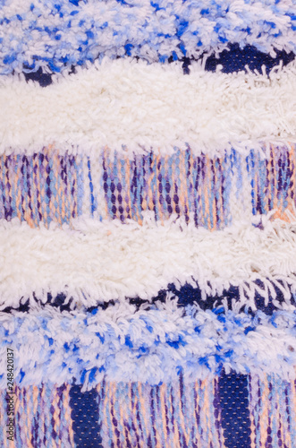 Vertical fragment of tapestry with wool threads. Colorful fabric with fluffy texture and horizontal stripes. Multi colored background with close up of a traditional beautiful textile. Craft carpet.