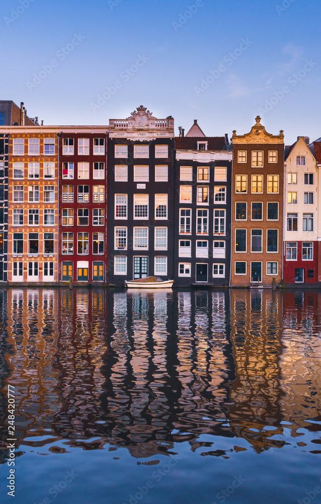 Front view of beautiful colorful traditional Amsterdam houses on the Amstel river bank reflecting in the river. Traditional dutch architecture