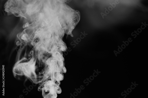 White smoke on a black background. Texture of smoke. Clubs of white smoke on a dark background for an overlay