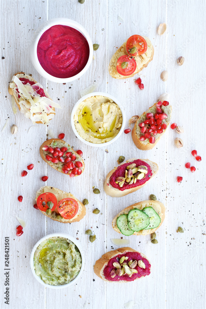 Variety of toasts or bruschetta on white background. Beetroot, avocado and hummus sauce. Flat lay Variety of toasts or bruschetta on white background. Beetroot, avocado and hummus sauce. Flat lay