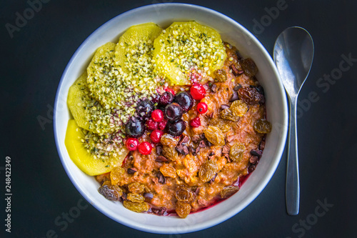 Breakfast oatmeal porridge with cinnamon, cranberries and blueberries, front view, selective focus