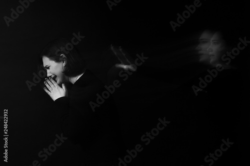 The girl is sad and crying, in the background is a ghost, a phantom. Black and white.