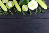 Green fruits, vegetables and rosemary on black boards with a copy space. Avocado, lime, kiwi and green apple on wooden boards. Cucumbers and rosemary branches top view. Healthy food