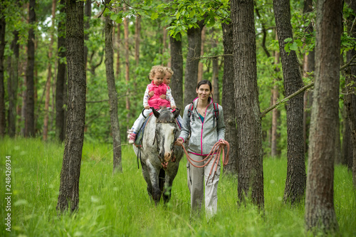 Girl having fun with mother and horse in the woods, young pretty girl with blond curly hair, freedom, joy, movement, outdoor, spring, healthy, happy family, cheerfull, kid on vacation