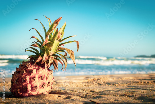 Fototapeta Naklejka Na Ścianę i Meble -  A pineapple on the beach, in the sand; drifted from the sea. Vacation mood and happy hour. With copyspace