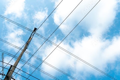 The wires that cross over on the electric pole under the blue sky. © thongchainak