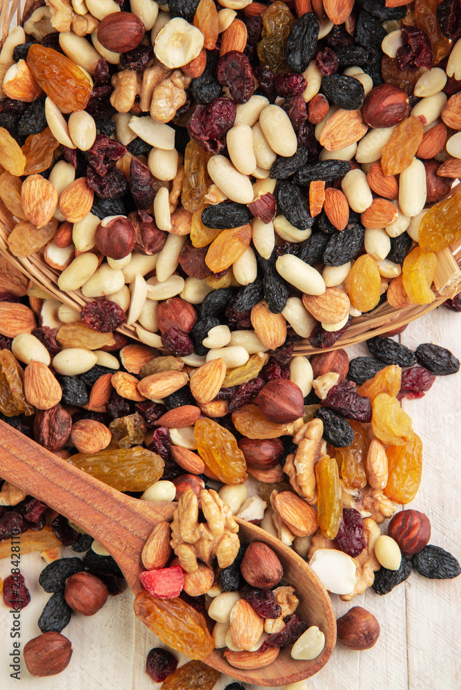 dried fruits and nuts on a wooden white background with a wooden spoon dried fruits and nuts on a wooden white background with a wooden spoon