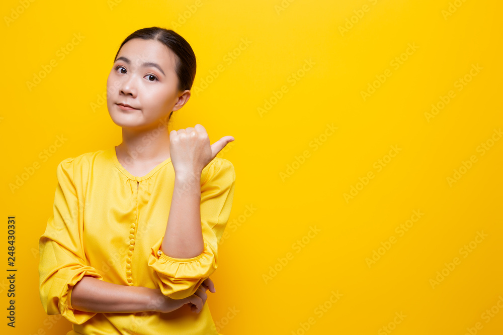 Woman pointing to copy space isolated over yellow background Woman pointing to copy space isolated over yellow background