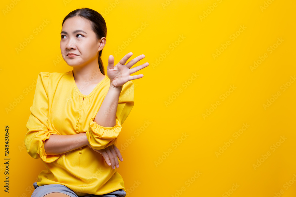 Woman show disgust gesture isolated over yellow background