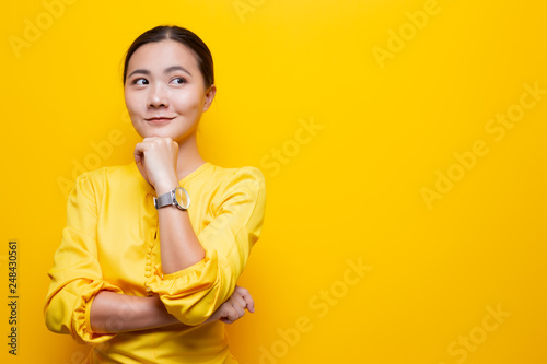 Happy woman thinking and standing isolated over yellow background