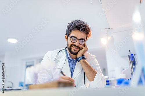 Male Doctor Writing On Medical Document