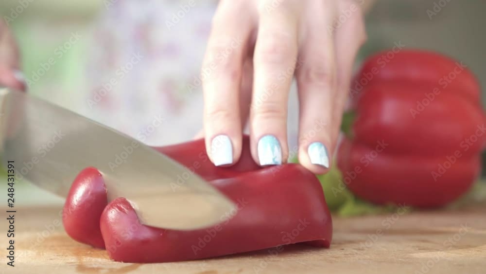 Woman in the kitchen cutting red pepper, slow motion. Woman in the kitchen cutting red pepper, slow motion.