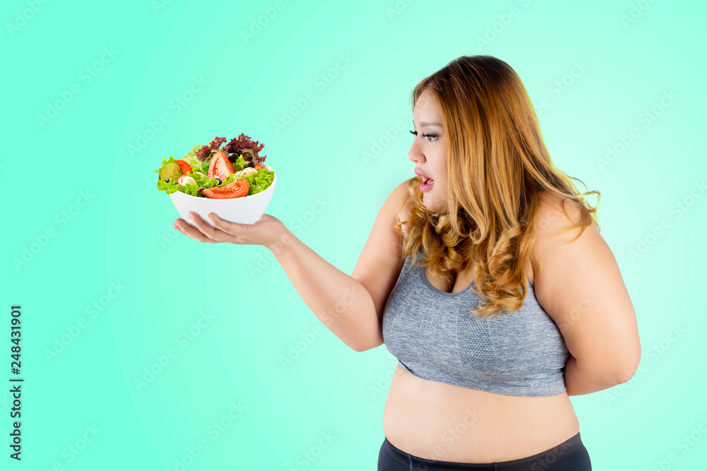 Caucasian fat woman holds bowl of healthy salad Caucasian fat woman holds bowl of healthy salad