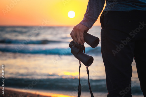 Close-up of binoculars in the hands of a man standing on the beach