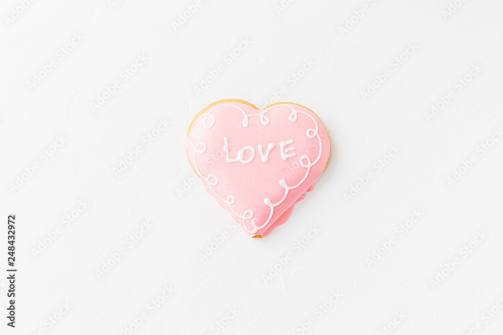 Heart shape cookie with love sign on white textured background Heart shape cookie with love sign on white textured background