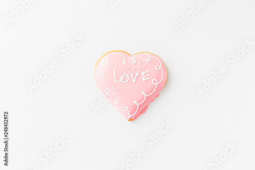 Heart shape cookie with love sign on white textured background