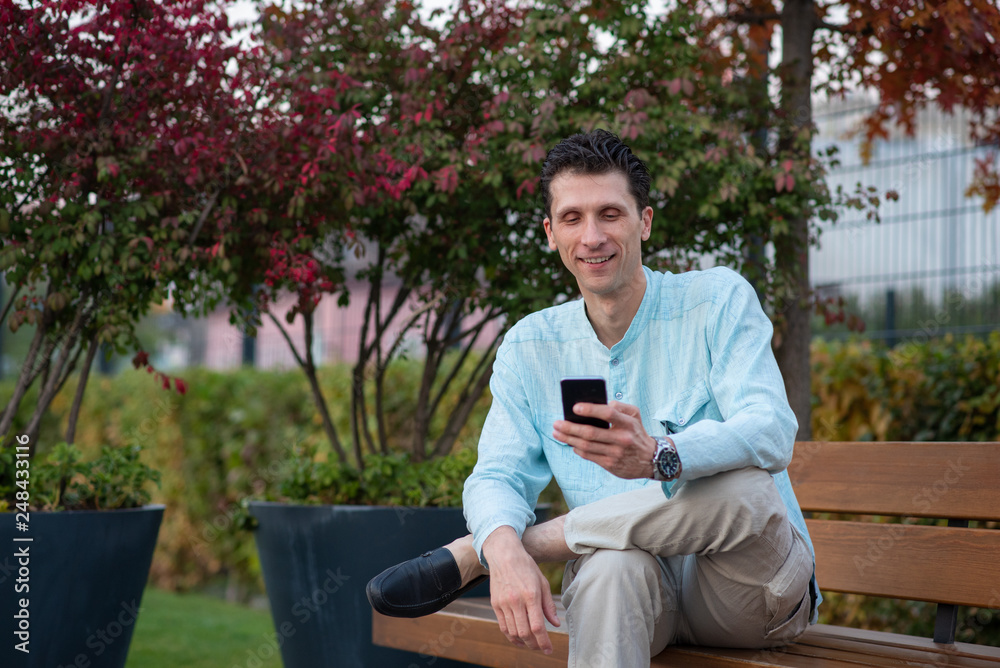 Fototapeta premium Handsome man using his mobile phone in a park