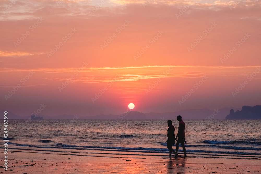 Silhouettes of people on a background of a sunset sea landscape
