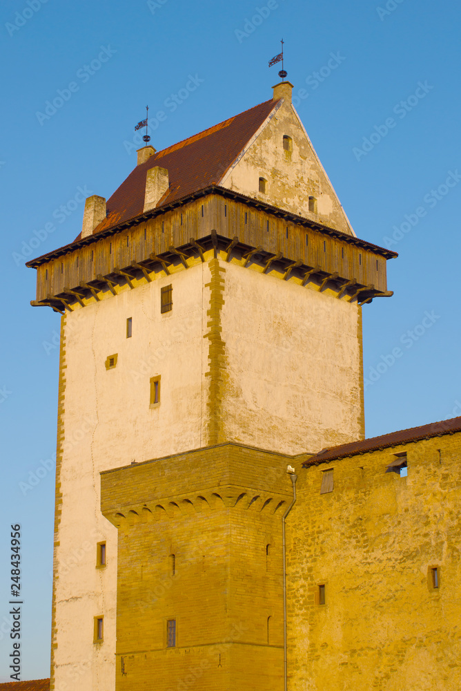 Main tower (Long Hermann) of the medieval castle of Narva close-up in the light of the setting sun. Narva, Estonia