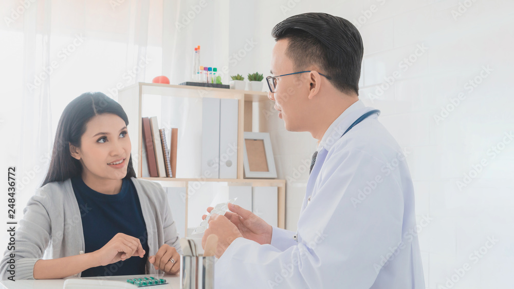 Professional doctor wearing white coat describe how to take medicine to woman patient in hospital background.Concept of disease treatment and health care in hospitals. Professional doctor wearing white coat describe how to take medicine to woman patient in hospital background.Concept of disease treatment and health care in hospitals.
