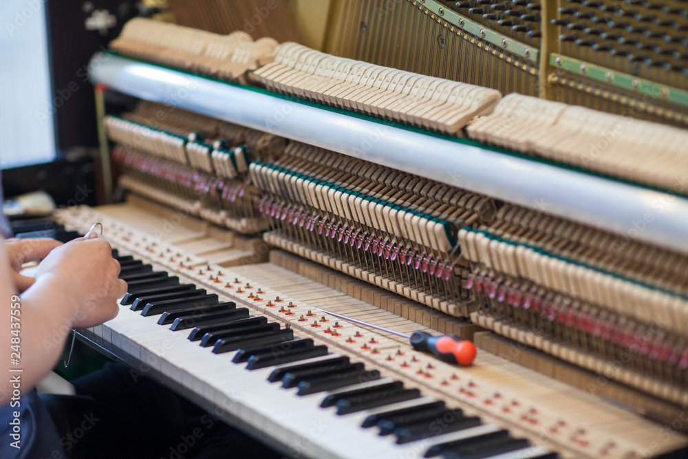 Musician or technician tuning piano using lever and tools Musician or technician tuning piano using lever and tools