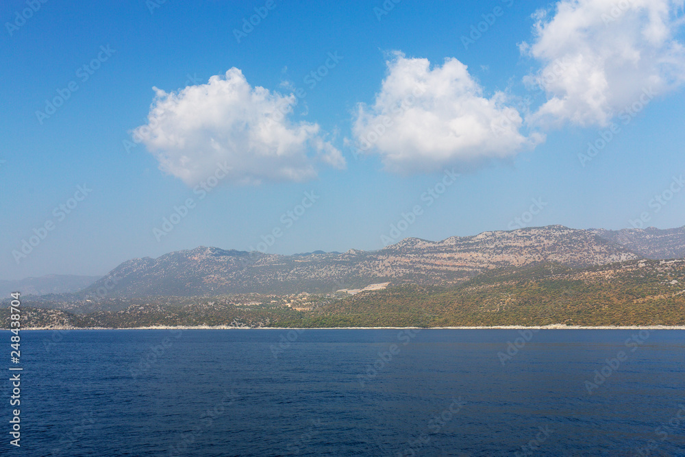 Mediterranean sea overlooking the mountains. Aerial top view of sea waves hitting rocks on the beach with turquoise sea water. Amazing rock cliff seascape in the coastline.