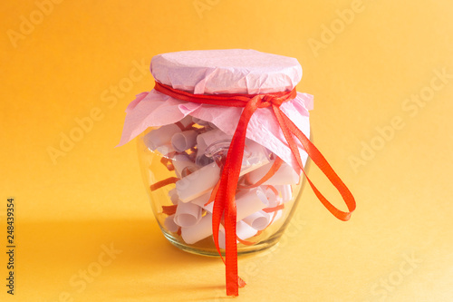Desires, Wishes or Dreams written on rolled papers in glass jar on yellow