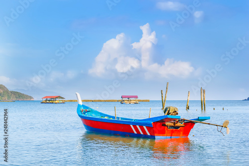 Traditional asian fishing boat anchored against blue sky with clouds on a sunny morning. Copy space