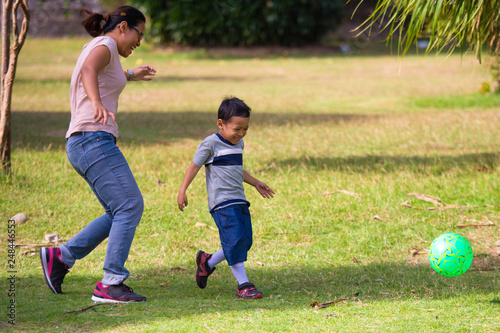 happy Asian Indonesian mother playing football with little 5 years old son running together excited laughing having fun in soccer fan child and healthy lifestyle education photo