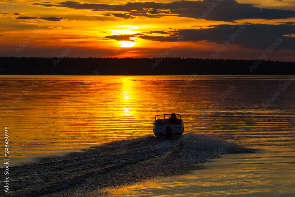 Boat sails on the lake at sunset