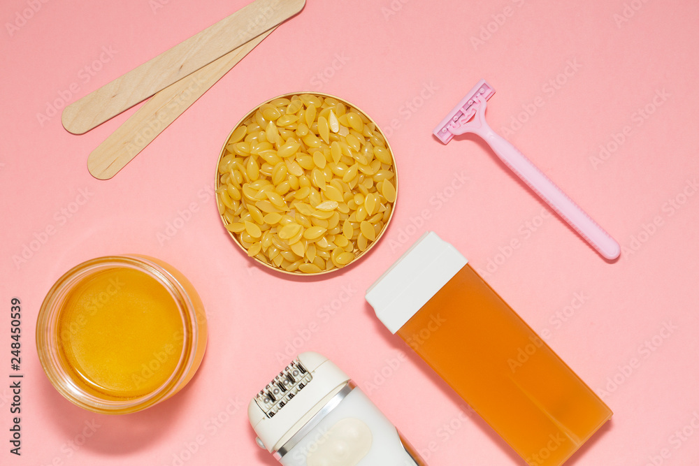 Beauty, depilation and hair removal concept - wax, spatula, epilator and safety razor on pink background. Top view. Beauty, depilation and hair removal concept - wax, spatula, epilator and safety razor on pink background. Top view.