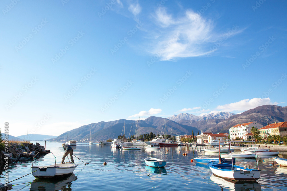 a fisherman moors a boat on the background of a Mediterranean town and yachts