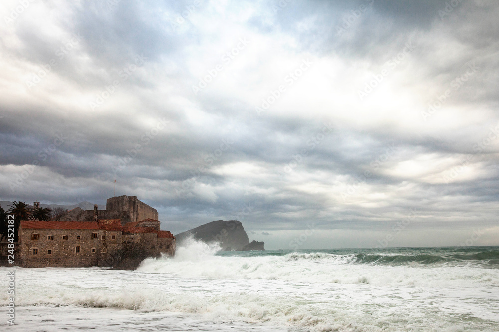 raging sea with huge waves that fall on an old Mediterranean fortress