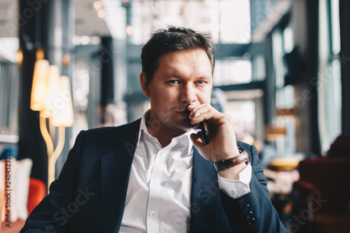 Close-up portrait of good looking young businessman with high self-esteem, sitting in a bar, posing for the camera.